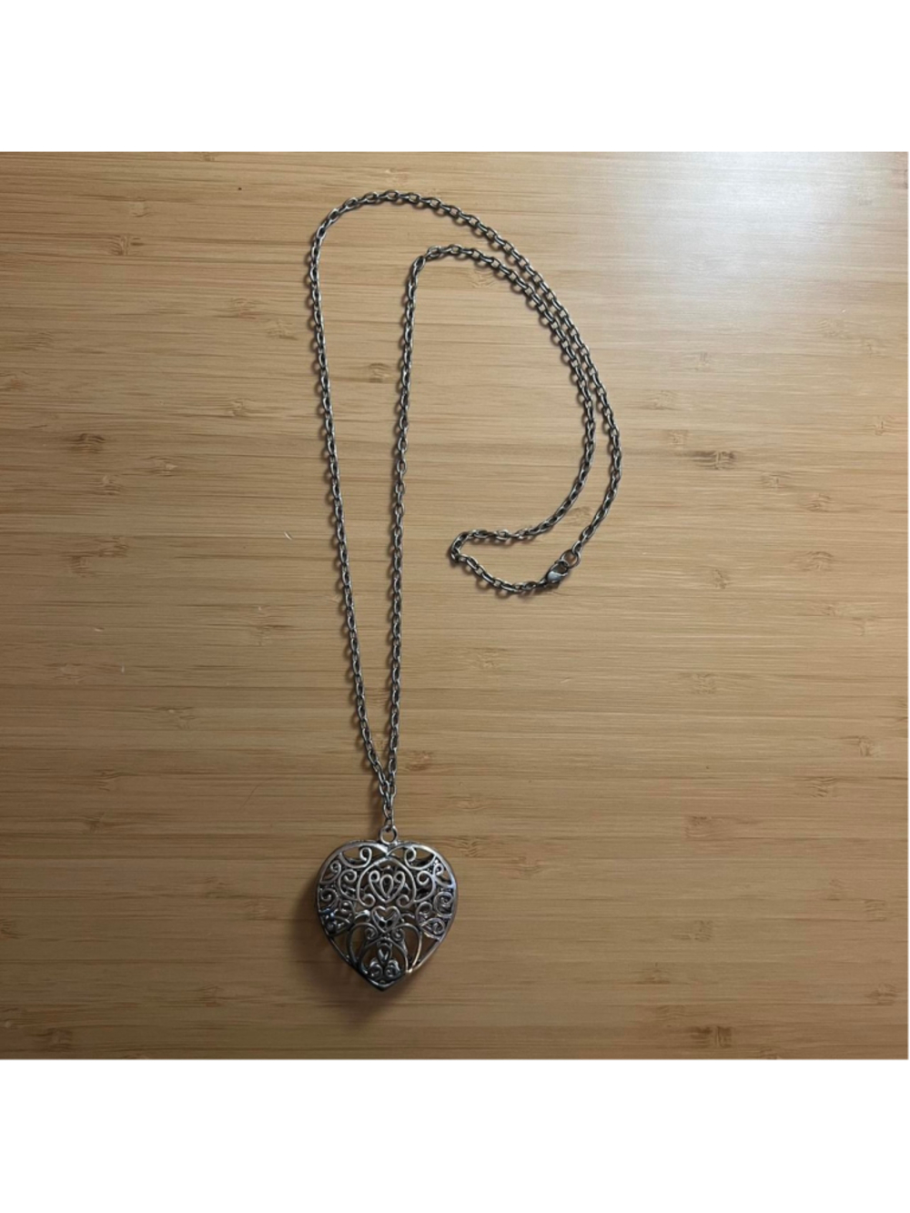 Long silver necklace with intricate heart pendant